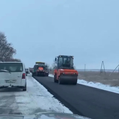 Асфальтирование на замерзшей дороге во время снегопада
