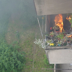 Жінка викидає ковдру з палаючим балкону
