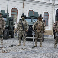 Людина розмінує землю українською прапорами