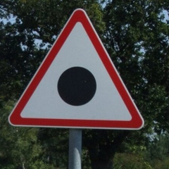 Чорна крапка у трикутнику на дорожньому знаку