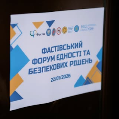 Жінка з мікрофоном на фоні прапора
