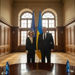 Дві жінки рукуються на фоні прапорів