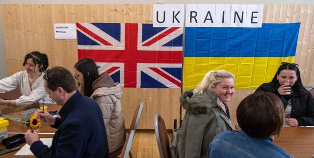 група мігрантів на тлі будинків у Британії