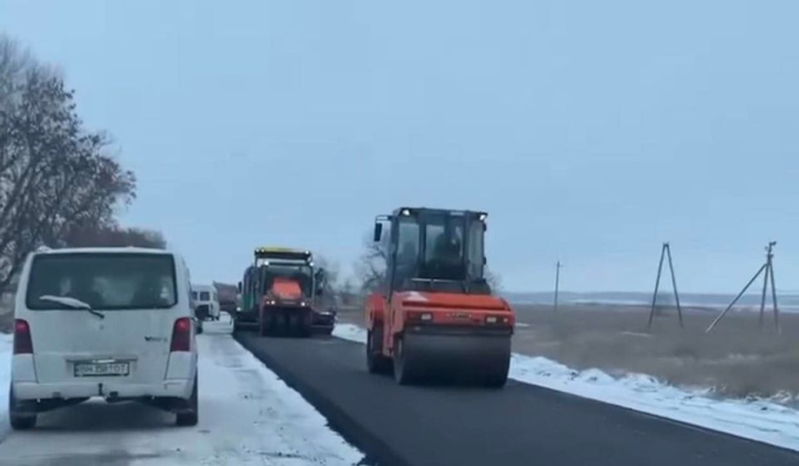 Асфальтування на крижаній дорозі під час снігопаду