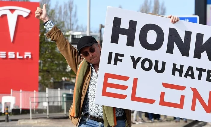 Протестующие с надписью 'Не финансируйте фашистов' напротив изображения Маска и Tesla