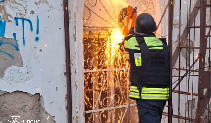 Спасатели выводят женщину из горящего здания