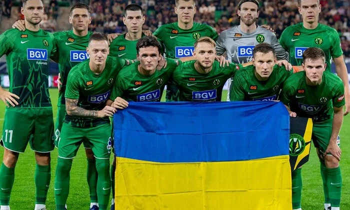 Логотип ФК Полісся і ФК Фіорентина на фоні футбольного поля