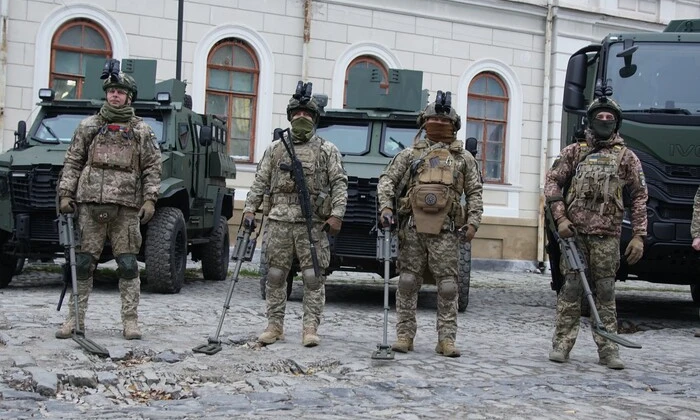 Людина розмінує землю українською прапорами