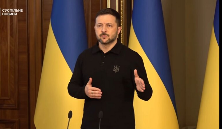 Зеленський на фоні прапорів України