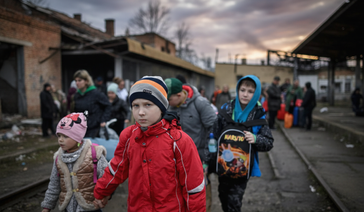 Children with haunted eyes standing on war remnants