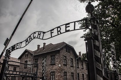Туристка жовтамвореного одміни біля воріт Освенціму