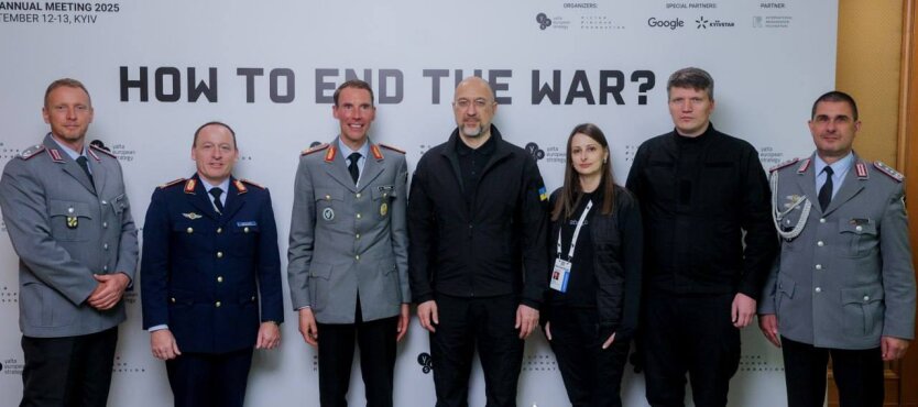 Логотип Україна-Німеччина на тлі зброї